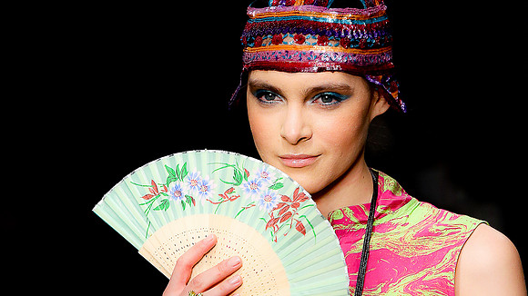 A photograph of a  model at London Fashion week holding a fan