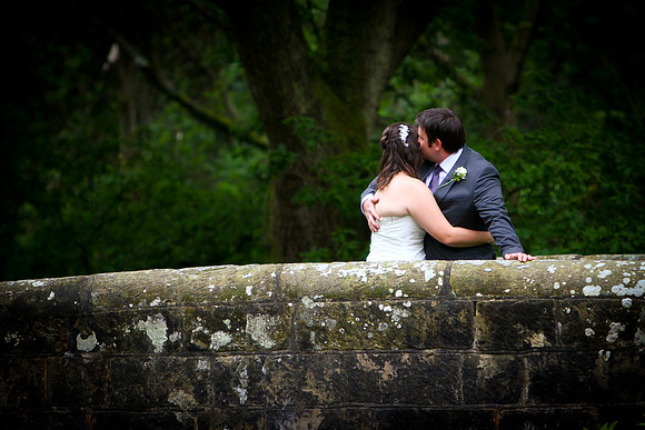 A newly wed couple embracing on a bridge